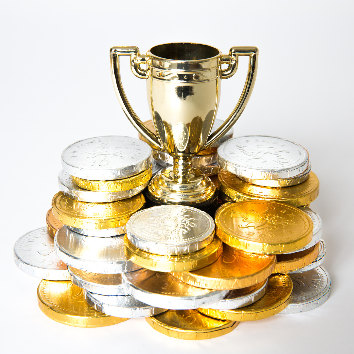 A golden trophy surrounded by gold and silver coin prize money for competitive success